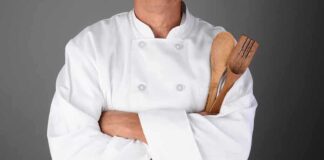 Industrial Mixer Horror: Chef’s Tragic Fate A chef in a white uniform holding wooden cooking utensils with crossed arms