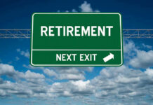 Green road sign reading retirement next exit sky background