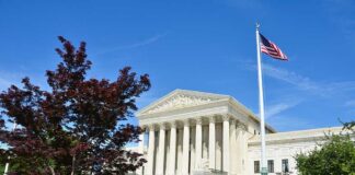 Supreme Court building with American flag and surrounding greenery
