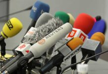 A collection of various microphones arranged for a press conference