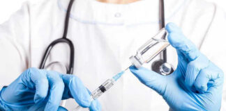 Doctor filling syringe with vaccine from vial.