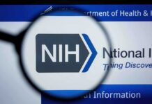 NIH logo displayed on a digital screen, viewed through a magnifying glass