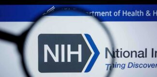 NIH logo displayed on a digital screen, viewed through a magnifying glass
