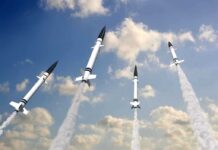 Multiple missiles launching into a cloudy sky