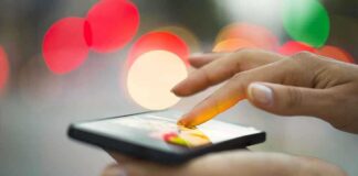 A person using a smartphone with a colorful bokeh background
