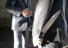 Two men shaking hands, one holding hidden knife.
