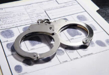 Only Witness Arrested After Wife Vanishes Handcuffs on fingerprint form with fingerprints visible.