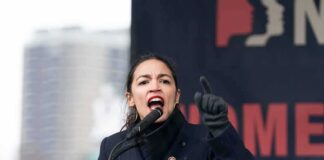 A woman passionately speaking at a podium during a rally