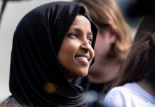 A woman wearing a black hijab smiling at an outdoor event