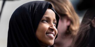 A woman wearing a black hijab smiling at an outdoor event