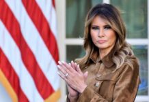 SMEAR CAMPAIGN Exposed—Melania Fights Back A woman in formal attire clapping in front of an American flag