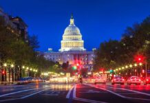 The U.S. Capitol building illuminated at night with city traffic in the foreground