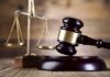 A wooden gavel and scales of justice on a wooden surface