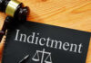 Explosive Allegations: TOP DOJ Prosecutor INDICTED Gavel next to indictment document on wooden table.