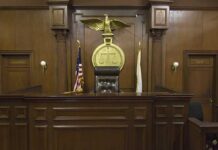 Interior of a courtroom featuring a judges bench and American flag