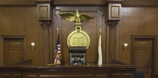 Interior of a courtroom featuring a judges bench and American flag