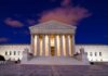 The Supreme Court building illuminated at night with a clear sky