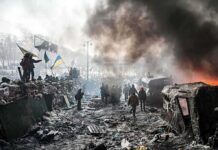 Kremlin’s SHOCKING Accusation — But Is It True? A chaotic protest scene with smoke, fire, and people holding flags