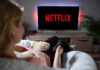 Netflix SPYING Allegation: DARK PATTERNS EMERGE Person watching Netflix on TV with popcorn and remote