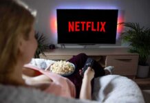 Person watching Netflix on TV with popcorn and remote