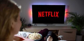 Person watching Netflix on TV with popcorn and remote