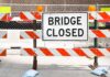 A Bridge Closed sign surrounded by safety barriers and fencing