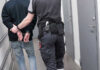 Federal Government Sues Over Limits on ICE and Other Agents Officer escorting handcuffed person down hallway.