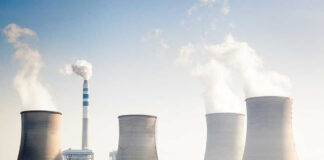 Four cooling towers of a power plant emitting steam.