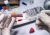 Gloved hands holding evidence swab in laboratory.