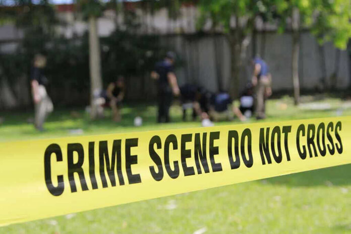 308657879 Yellow crime scene tape blocking grassy area.