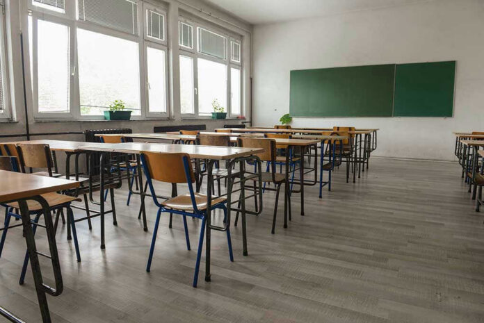 487861393 Empty classroom with desks, chairs, windows, and chalkboard.