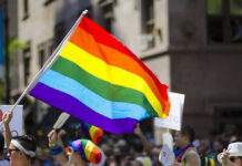 Firestorm Erupts: Bible Verses Ignites MLB Controversy People holding and waving a rainbow flag.