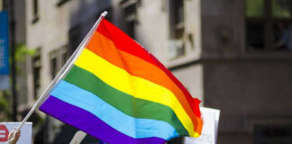Firestorm Erupts: Bible Verses Ignites MLB Controversy People holding and waving a rainbow flag.