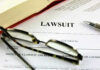 Massive 23andMe Data Breach Payout Approved Lawsuit paperwork with glasses, pen, and an open book.