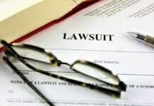 Massive 23andMe Data Breach Payout Approved Lawsuit paperwork with glasses, pen, and an open book.