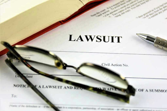775833220-2 Lawsuit paperwork with glasses, pen, and an open book.