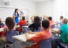 Classroom Power Flip Stuns America Teacher in a blue dress instructing students in a classroom with hands raised