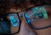 Media Meltdown Over Trump Trades Close-up of a persons eyes with financial data reflected in their glasses