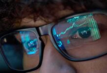 Media Meltdown Over Trump Trades Close-up of a persons eyes with financial data reflected in their glasses