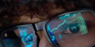 Media Meltdown Over Trump Trades Close-up of a persons eyes with financial data reflected in their glasses