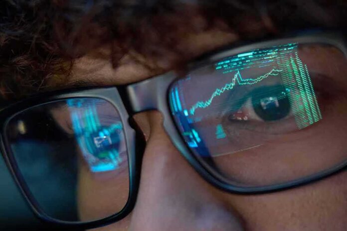 shutterstock_2146725931 Close-up of a persons eyes with financial data reflected in their glasses