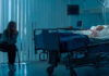 Hell to Heaven: Her Brain Never Left Woman sitting beside hospital bed at night.
