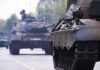 War Drills Next Door — Moscow Growls Tanks on a road with soldiers inside.