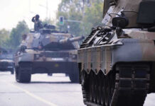 War Drills Next Door — Moscow Growls Tanks on a road with soldiers inside.