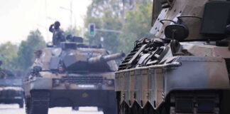 War Drills Next Door — Moscow Growls Tanks on a road with soldiers inside.