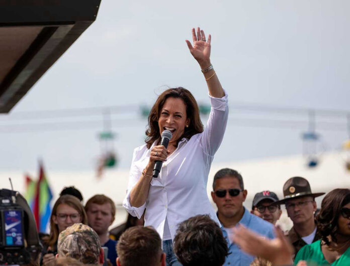 147618444 Person speaking with microphone, waving to outdoor crowd.