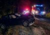 Crashed car on a dark roadside with emergency vehicles