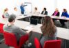 North American Trade Faces New Uncertainty A diverse group of professionals engaged in a meeting with a presenter at a whiteboard