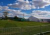 Circus Stunt Ends in Emergency Airlift Temporary white tents and equipment on a grassy field with traffic cones and metal barriers
