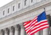 American flag waves in front of a United States courthouse facade